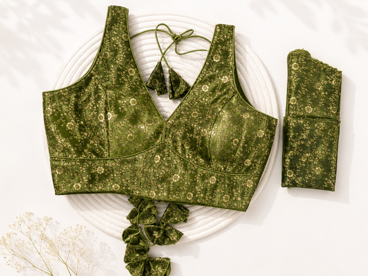 Green floral-patterned sports bra and leggings set on a white surface with dried flowers.